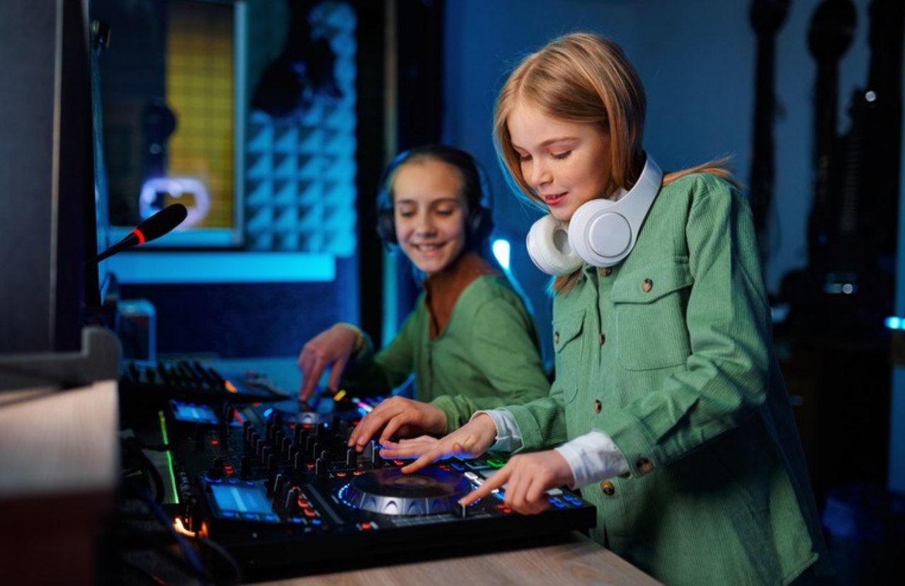 Twee meisjes samen achter een DJ-controller in een blauw verlichte studio